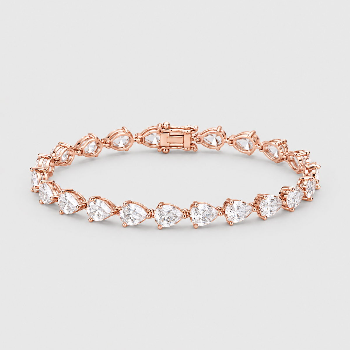 A rose gold tennis bracelet featuring a series of pear-cut clear gemstones in a classic four-prong setting, displayed on a neutral light gray background.