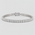 A silver tennis bracelet featuring a continuous row of baguette-cut clear gemstones in a polished silver setting, displayed on a light gray background.