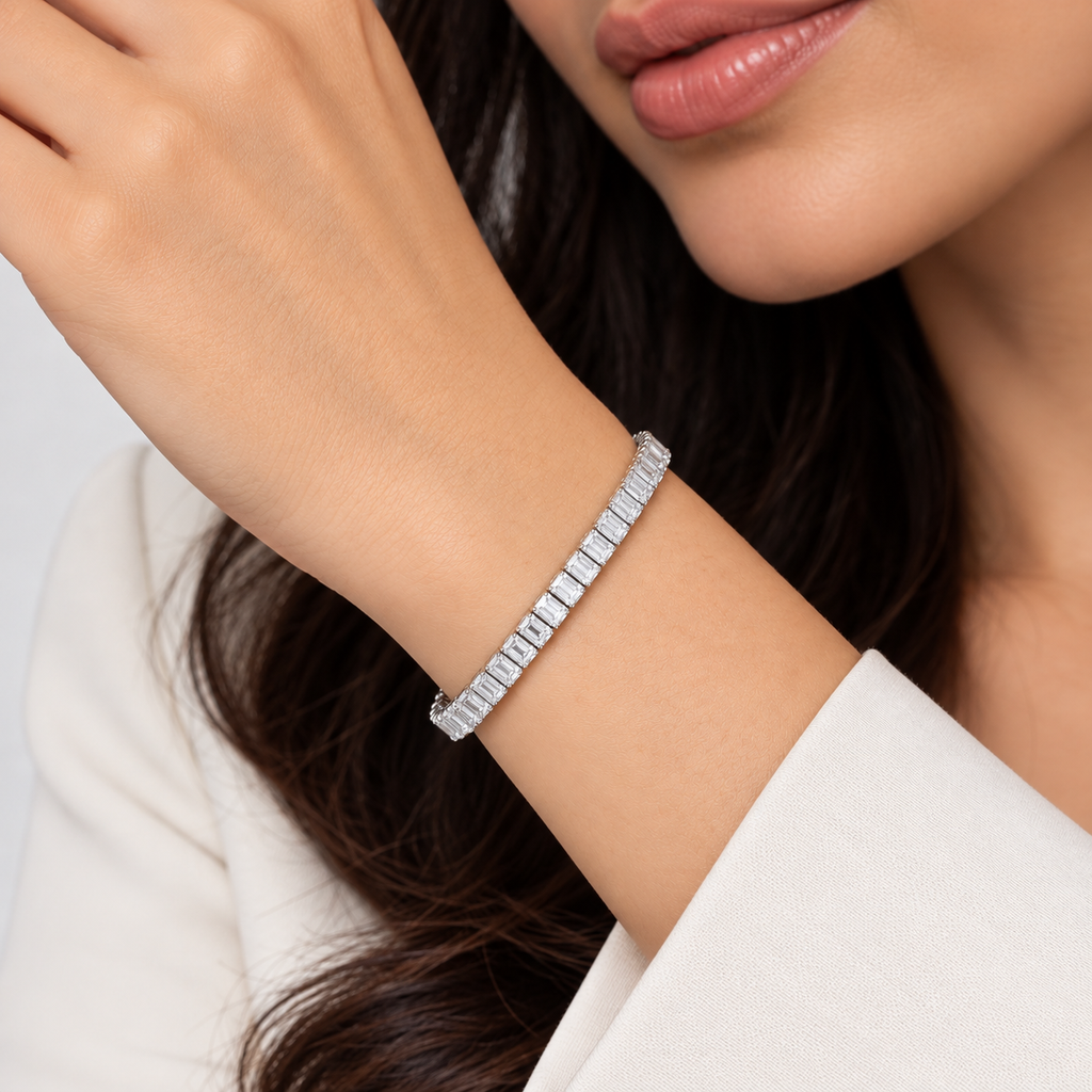 A close-up lifestyle shot of a woman wearing a silver tennis bracelet with baguette-cut stones on her wrist.