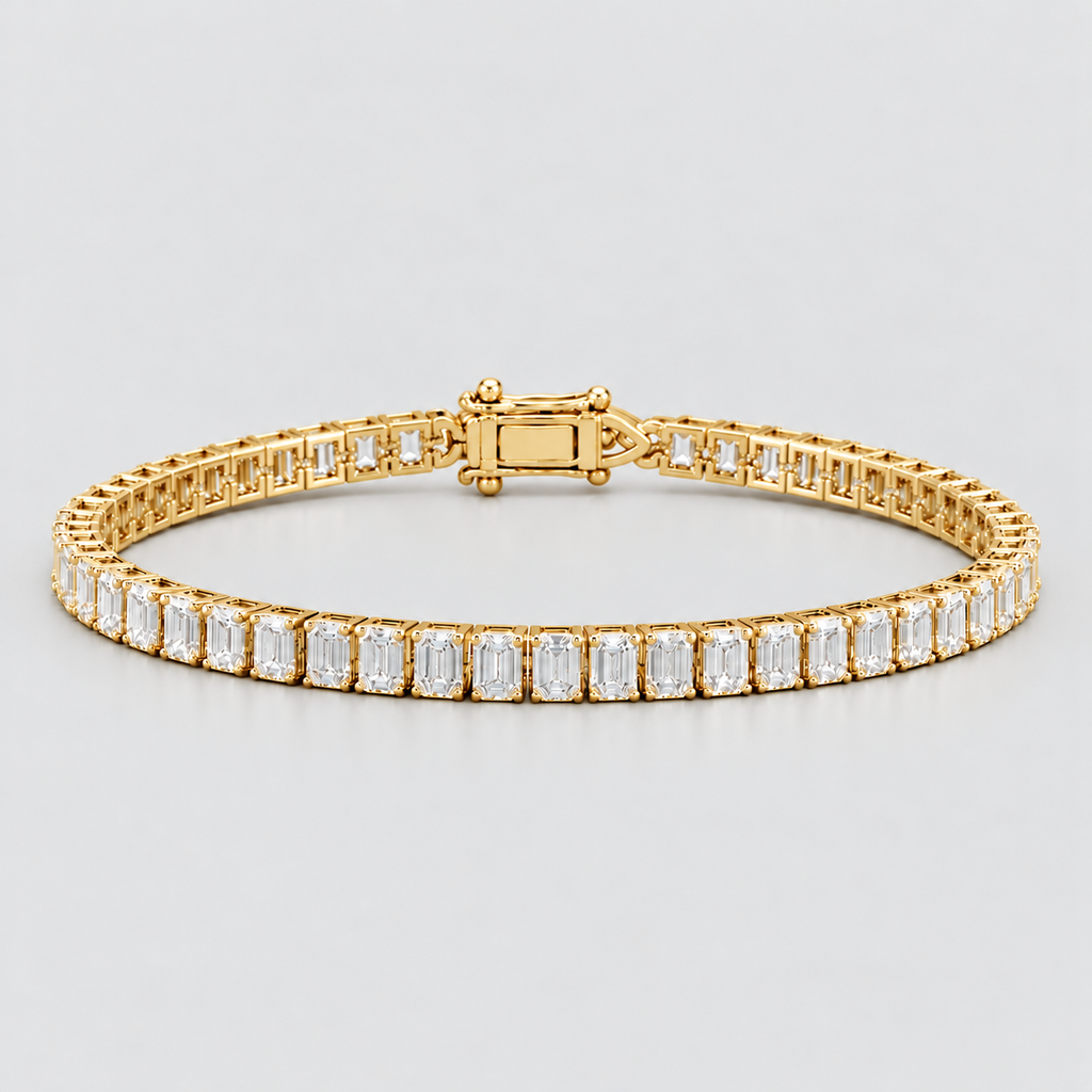 A yellow gold tennis bracelet featuring a continuous row of baguette-cut clear gemstones in a prong setting, shown against a neutral light gray background.